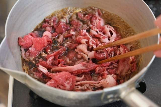 沸いた煮汁に肉をほぐし入れる